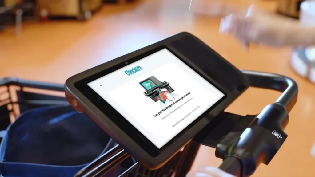 Shoprite concierge assisting a customer with age verification at a Checkers Xpress smart trolley lane.