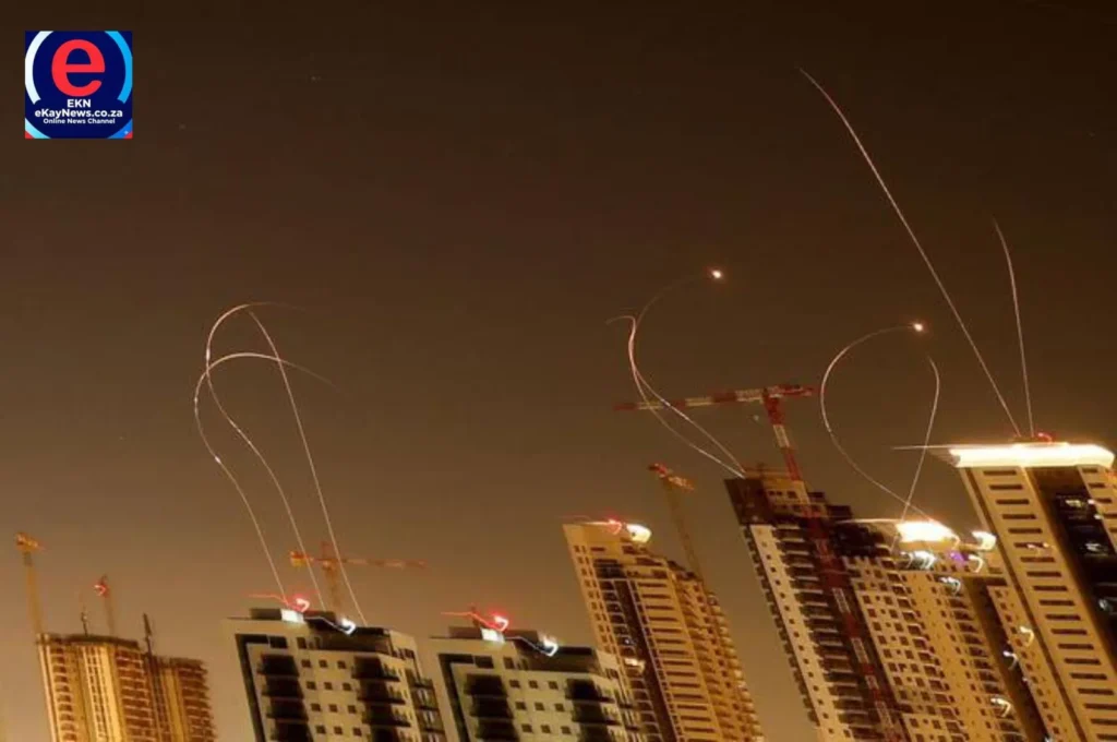 Iranian missile launches and simultaneous coastal city defenses with exploding bursts over a cityscape at night.