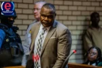 Suspended police sergeant Fannie Nkosi arrives at court under heavy guard facing corruption charges.